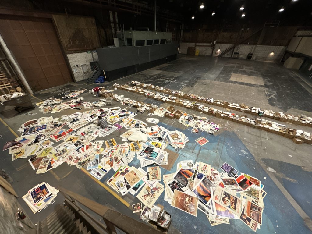 The floor of Stage 24 partially covered by rows of cardboard boxes and loose stacks of papers.