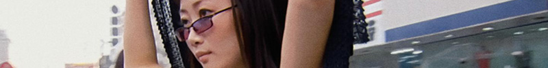 Tao Zhao, arms above head, wearing sunglasses, looking to the right. Part of her face and arms are visible.