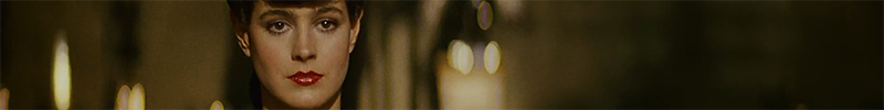 Sean Young as Rachael from Blade Runner. Just her face is visible. The background is unclear gold and brown shapes.